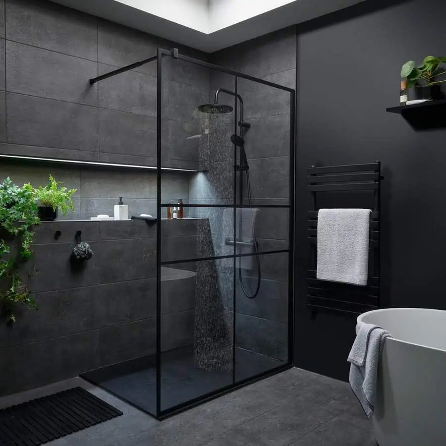 Sophisticated black bathroom with a glass shower, greenery accents, and modern lighting.