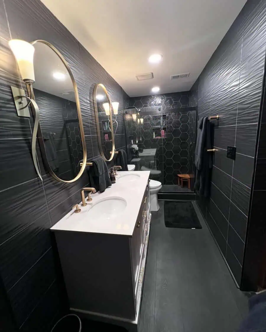 Spa-inspired black bathroom with gold-framed mirrors, hexagonal tiles, and a double vanity.