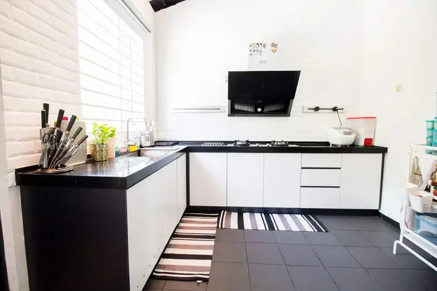 Space-saving L-shaped kitchen with a black and white color scheme, modern appliances, and sleek countertops.