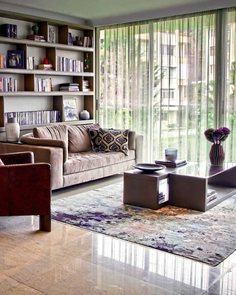 Spacious living room with open shelving, floor-to-ceiling windows, and modern cozy decor.