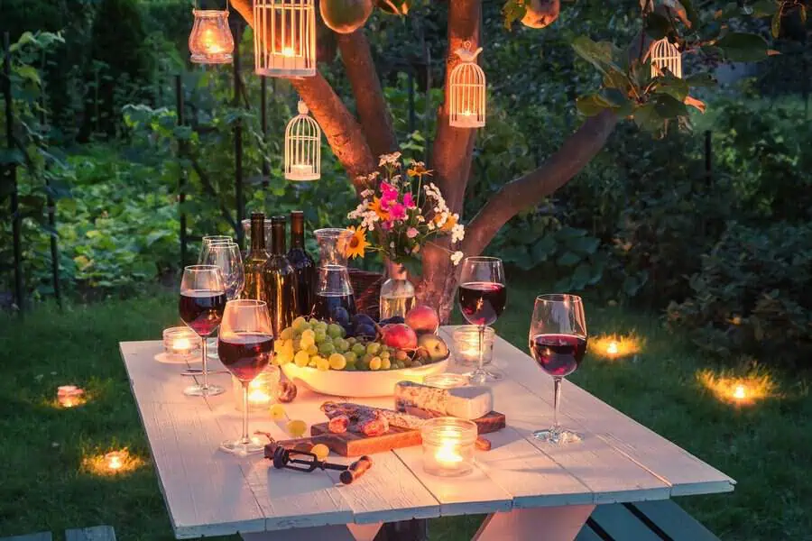 Spring garden housewarming party with a candlelit table, wine, fresh fruit, and a charming outdoor setting.