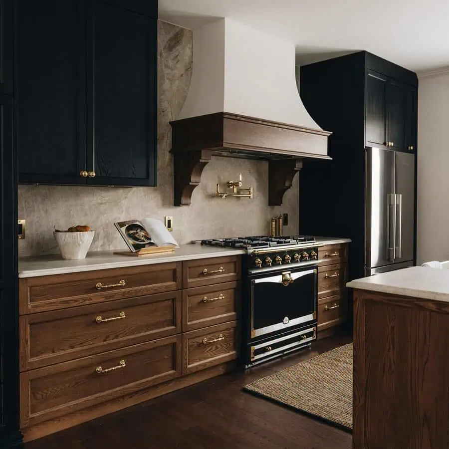 Striking two-tone kitchen with black and warm wood cabinets, brass hardware, and a vintage range.