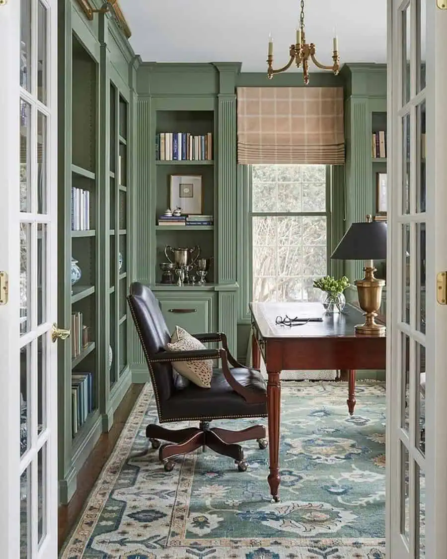 Study home library with sage green built-in bookshelves, a wooden desk, and a leather chair.