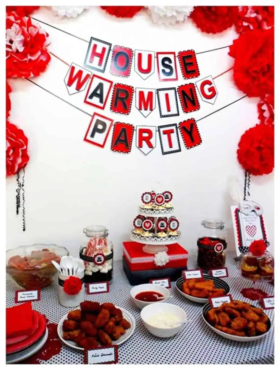 Themed housewarming party with red and white decor, festive banner, and assorted party snacks.