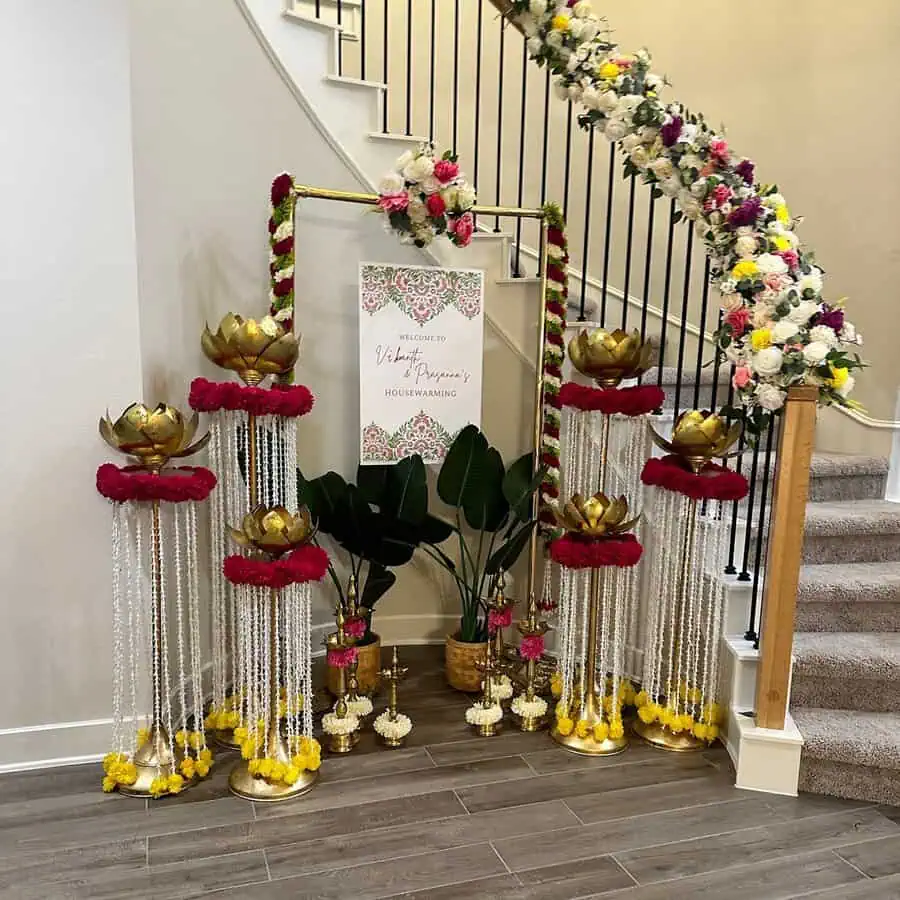 Traditional Indian housewarming decor with floral garlands, golden lotus accents, and an elegant welcome sign.