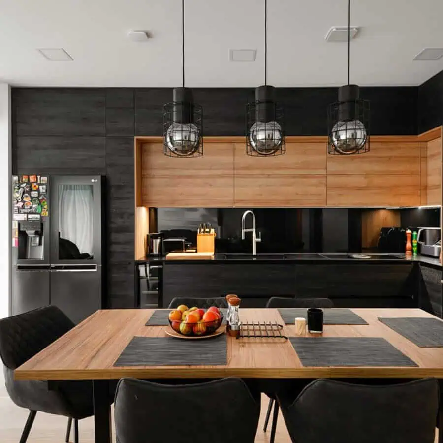 Striking two-tone kitchen with black and wood cabinets, industrial lighting, and a modern dining setup.