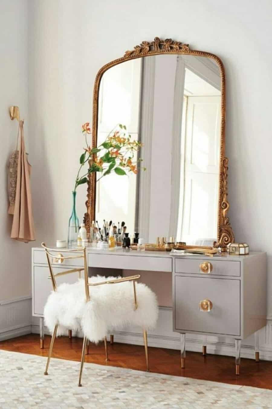 Chic vintage dressing table with a gilded mirror, modern gray desk, gold accents, and a plush fur chair.