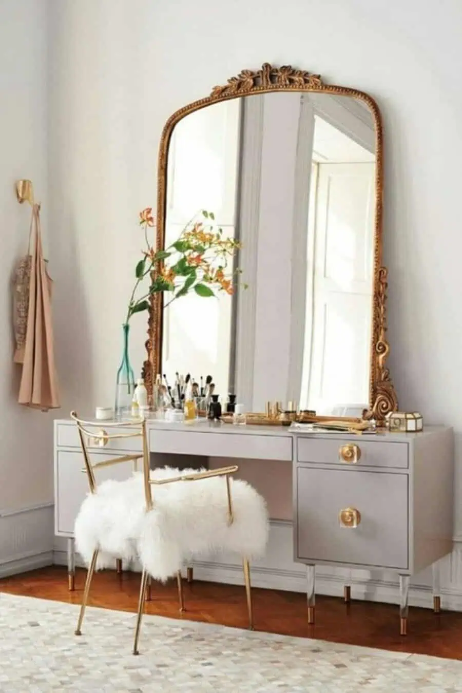 Chic vintage dressing table with a gilded mirror, modern gray desk, gold accents, and a plush fur chair.