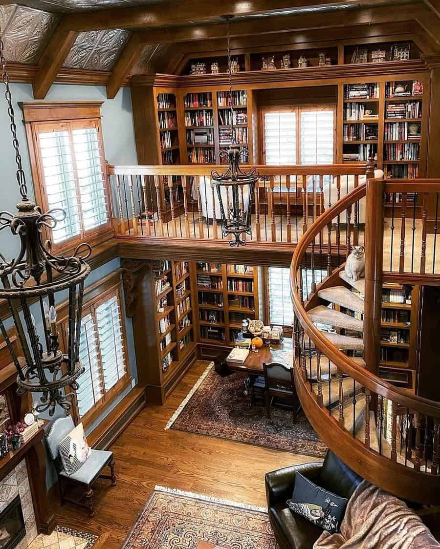 Grand two-story home library with wood paneling, spiral staircase, and vintage chandeliers.