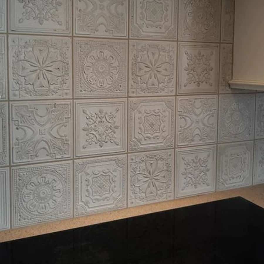 Antique white cabinets paired with a vintage embossed tile backsplash create a timeless, elegant kitchen.