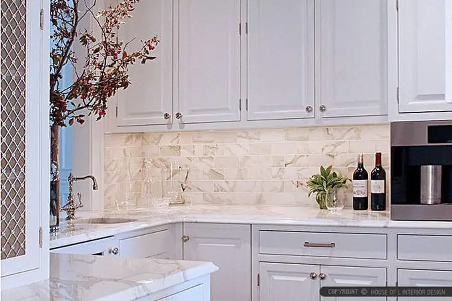 Warm-toned marble backsplash complements white cabinets for a luxurious and sophisticated kitchen look.