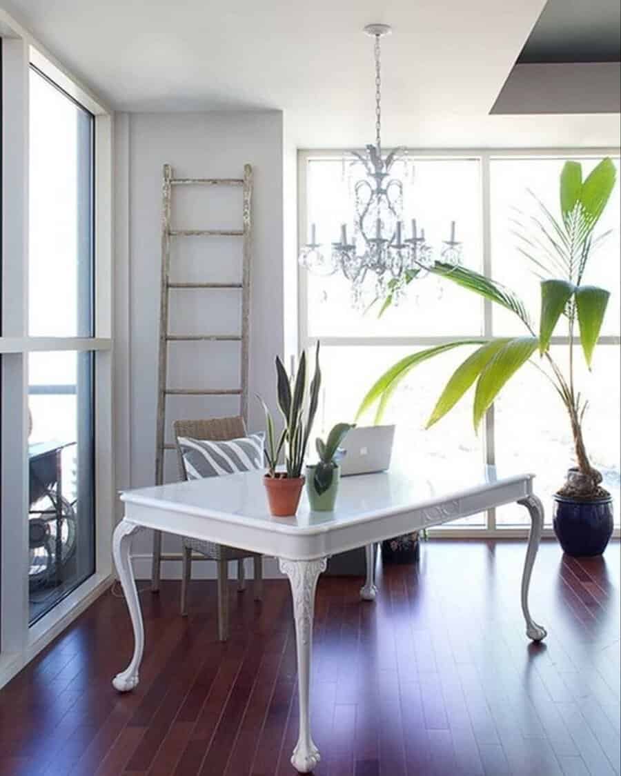Bright and airy home office with white furniture, plants, and a chandelier, bringing balance and elegance to the space.