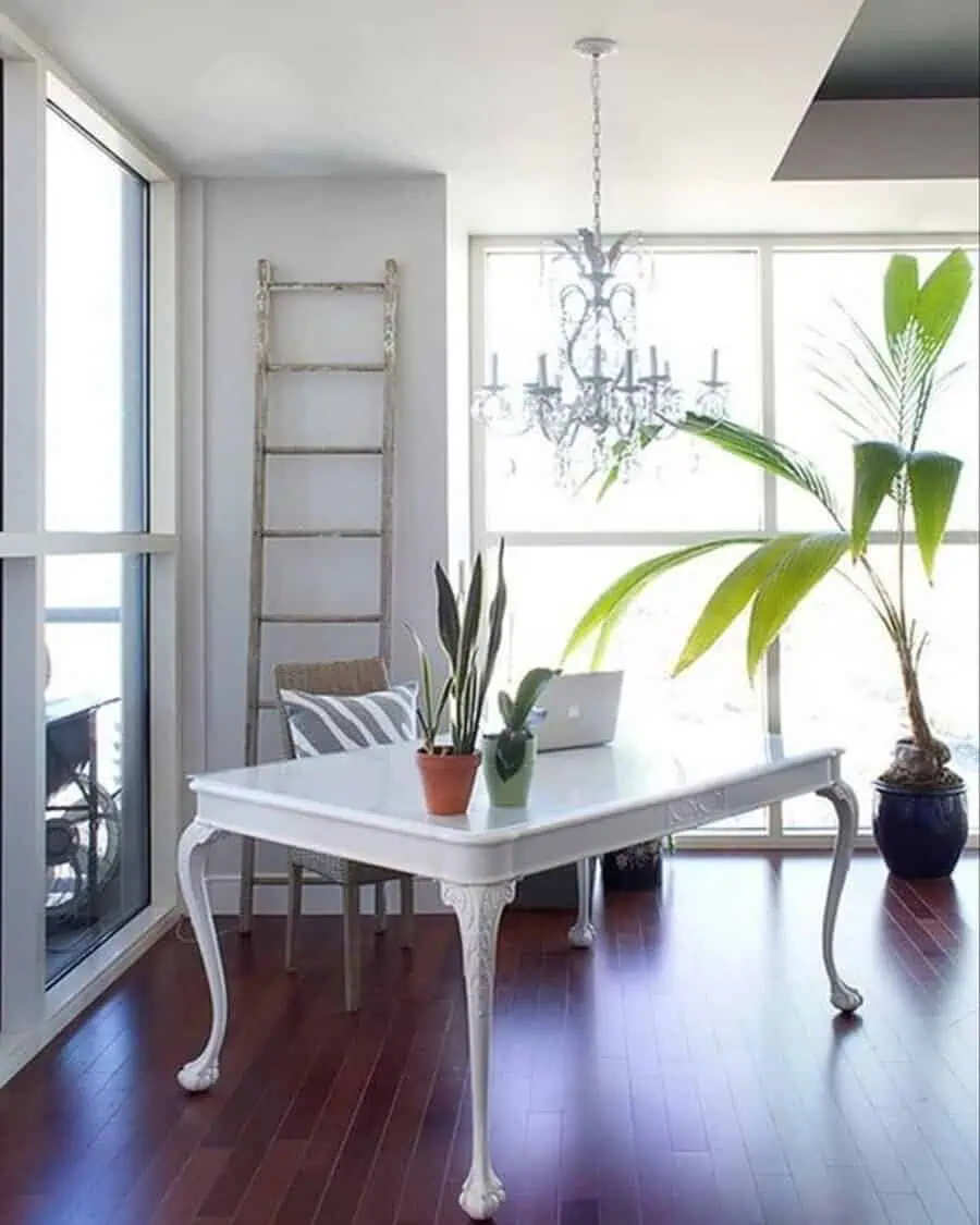 Bright and airy home office with white furniture, plants, and a chandelier, bringing balance and elegance to the space.