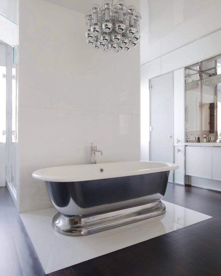 Chrome bubble chandelier above a black-and-chrome tub in a crisp white bathroom with dark flooring.