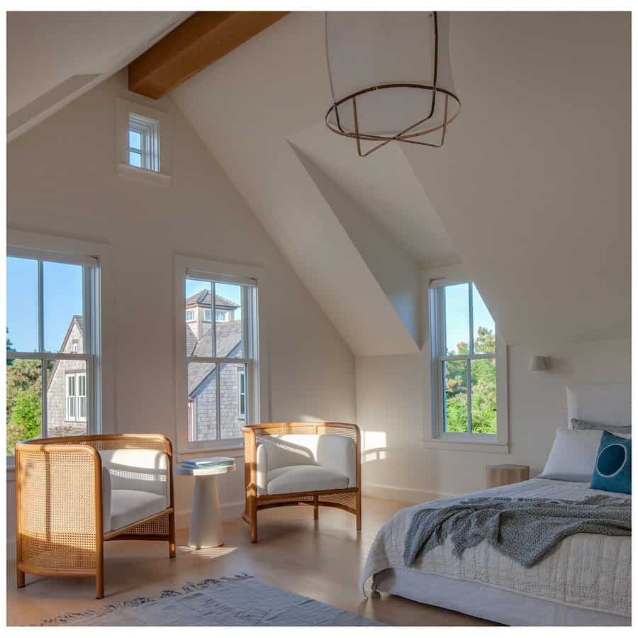 Bedroom sitting area with rattan chairs, neutral tones, large windows, and soft natural light for a relaxed and airy feel.