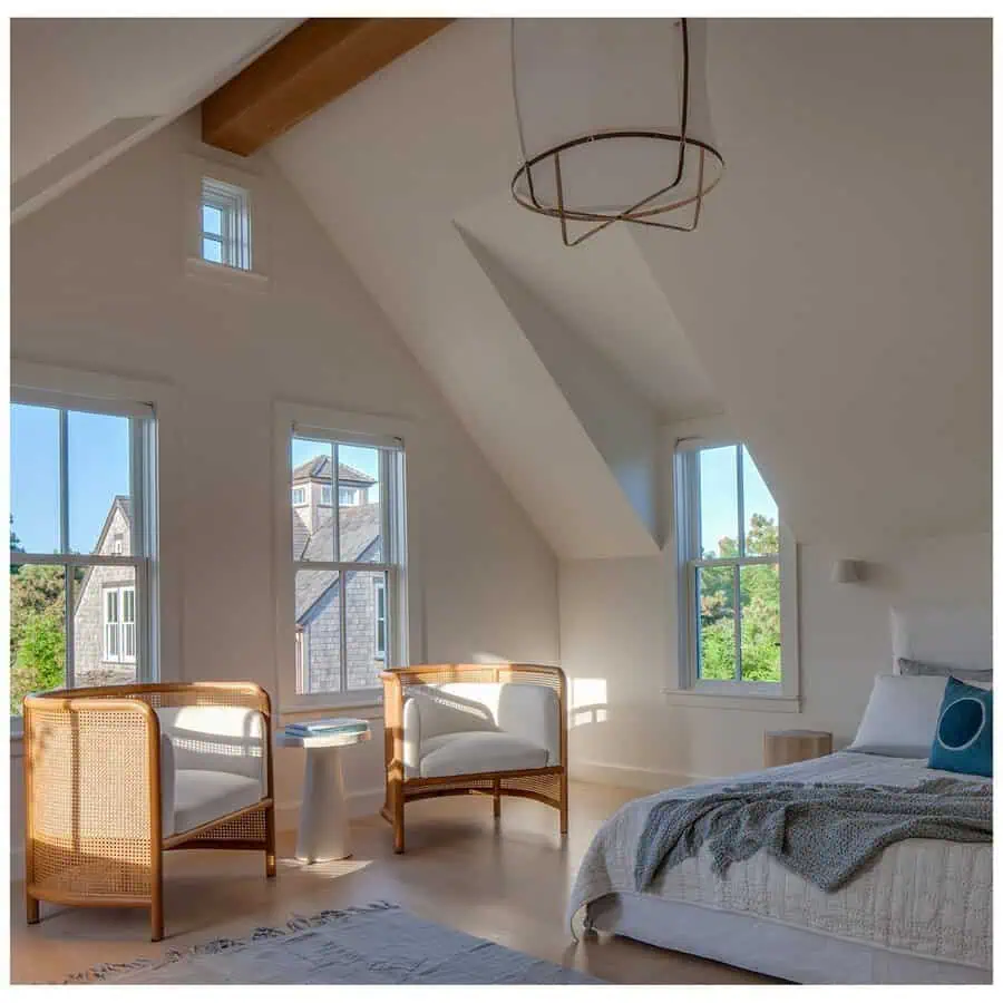 Bedroom sitting area with rattan chairs, neutral tones, large windows, and soft natural light for a relaxed and airy feel.