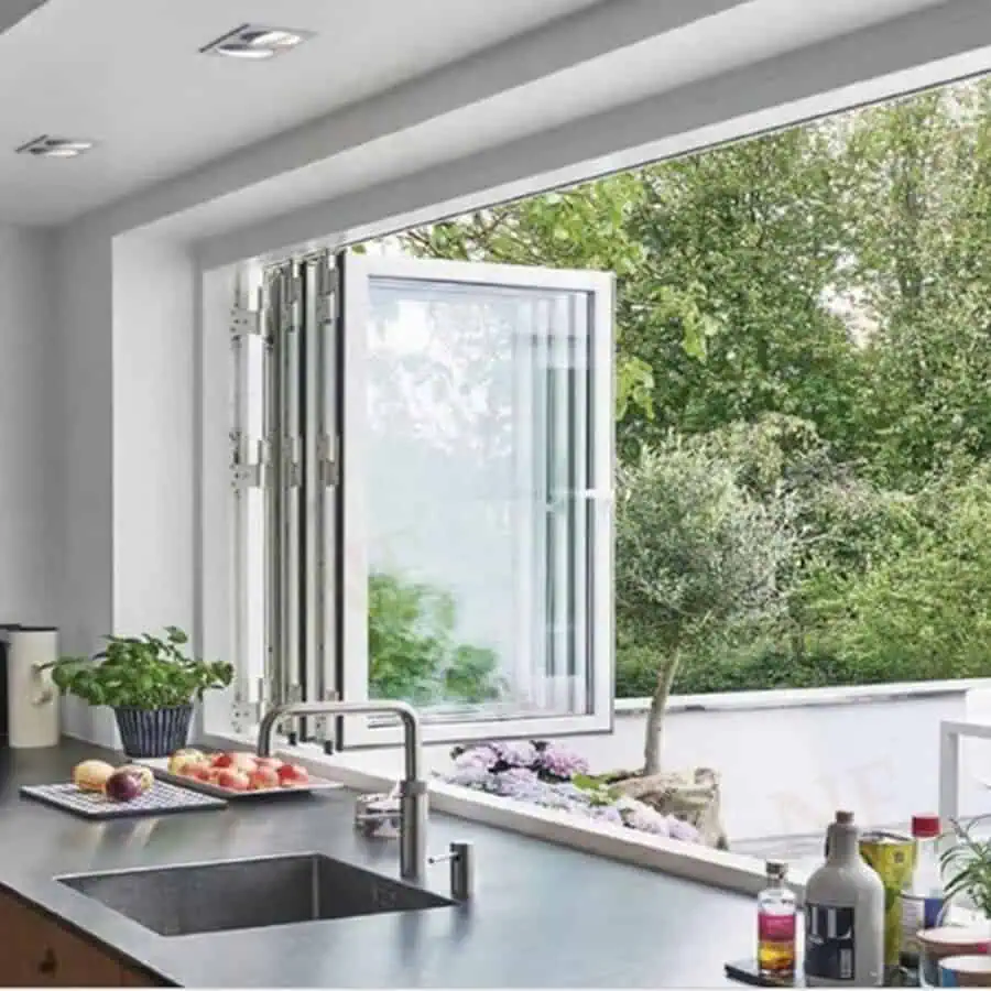 Kitchen with wide bifold windows leading to a green patio, sleek countertop, and a modern sink.