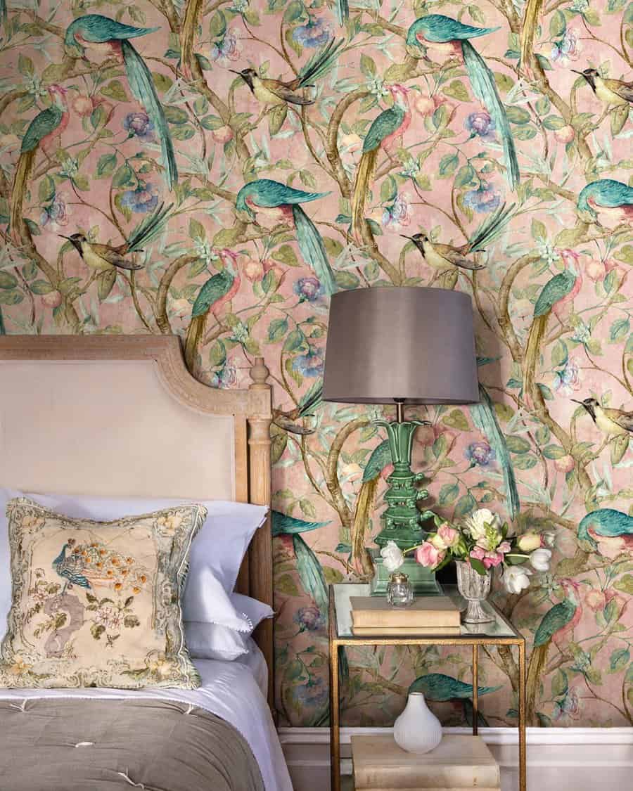 Bold pink wallpaper with botanical and bird motifs adds a dramatic yet elegant touch to a bedroom with vintage-inspired decor.