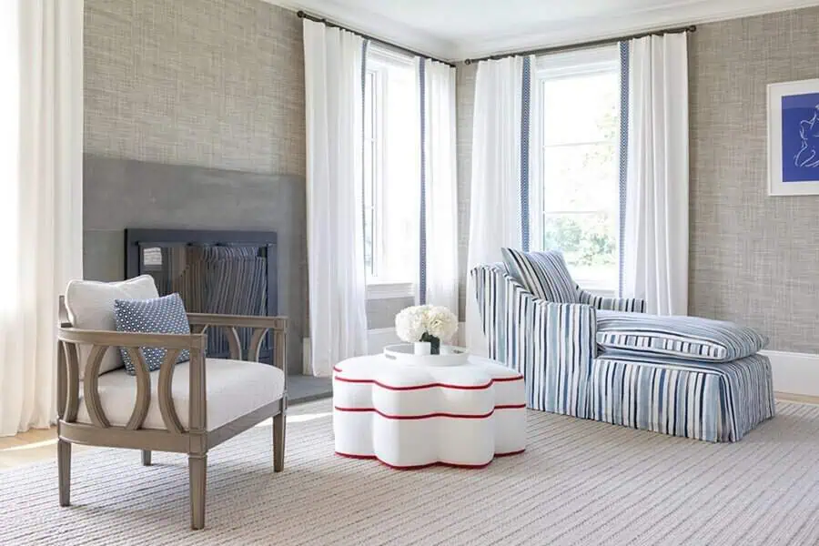 Bedroom sitting area with a sculptural wavy coffee table, striped chaise lounge, carved wood chair, and soft neutral tones.