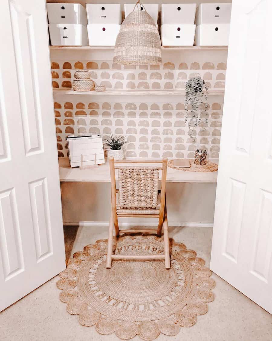 Small closet office with woven textures, rattan chair, pendant light, open shelving, neutral tones, and a cozy boho-inspired design.