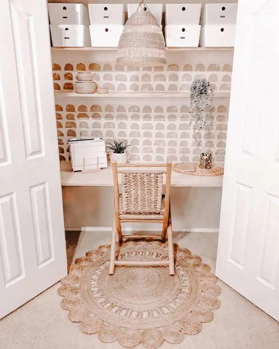 Small closet office with woven textures, rattan chair, pendant light, open shelving, neutral tones, and a cozy boho-inspired design.