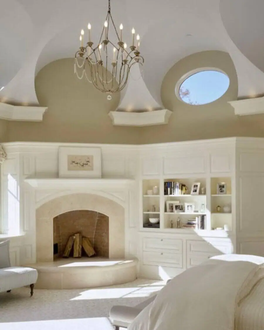 Room with a dome-like ceiling, round skylight, chandelier, built-in shelves, and a large arched fireplace in a neutral palette.