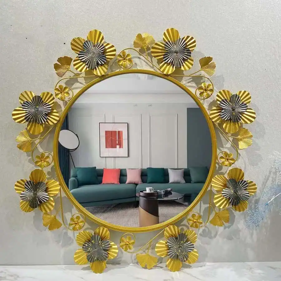 Floral-framed mirror reflecting a modern living room with a green sofa and colorful cushions.