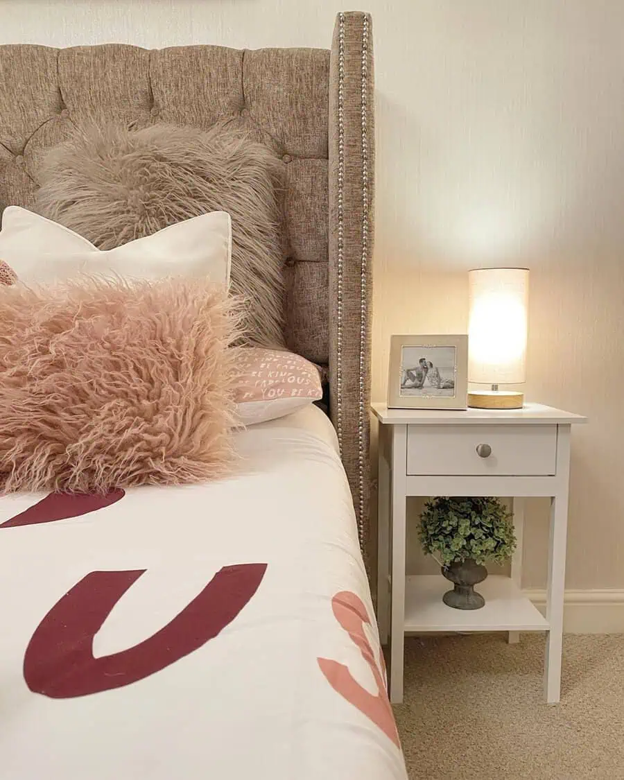 Soft blush and neutral fluffy pillows add warmth and texture to a cozy, elegant bedroom setup.