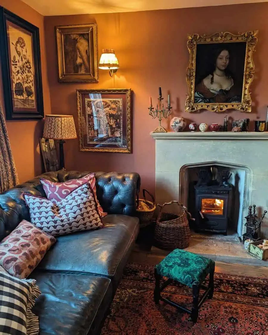 Terracotta-walled sitting room with a Chesterfield sofa, stone fireplace, gilded frames, and layered patterns for a warm, eclectic feel.