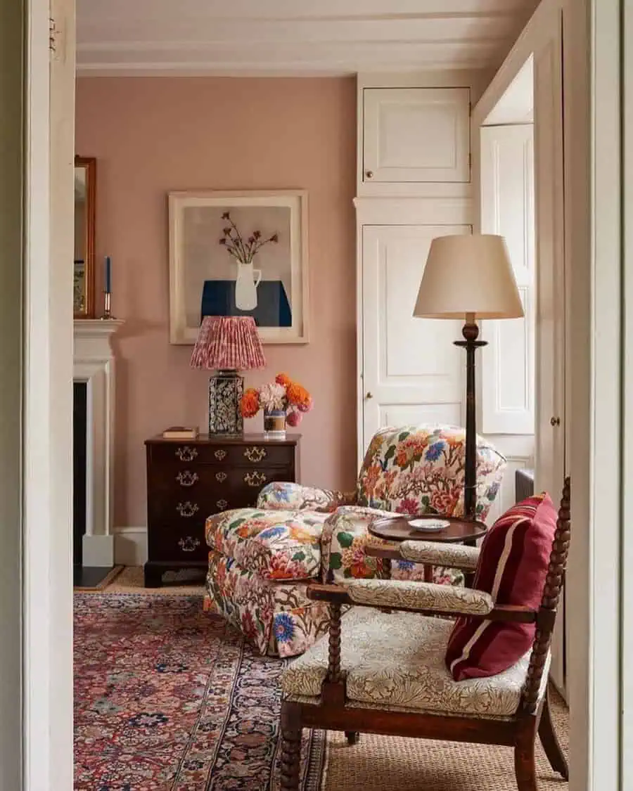 Cozy Georgian sitting room with floral armchair, antique chest, soft peach walls, and a patterned rug for a warm, inviting feel.