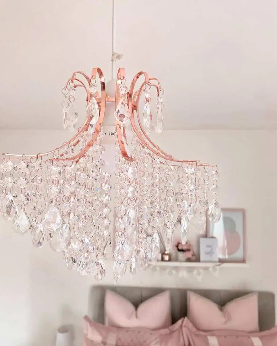 Rose gold chandelier with cascading crystals adds a glamorous and elegant touch to a soft pink bedroom.