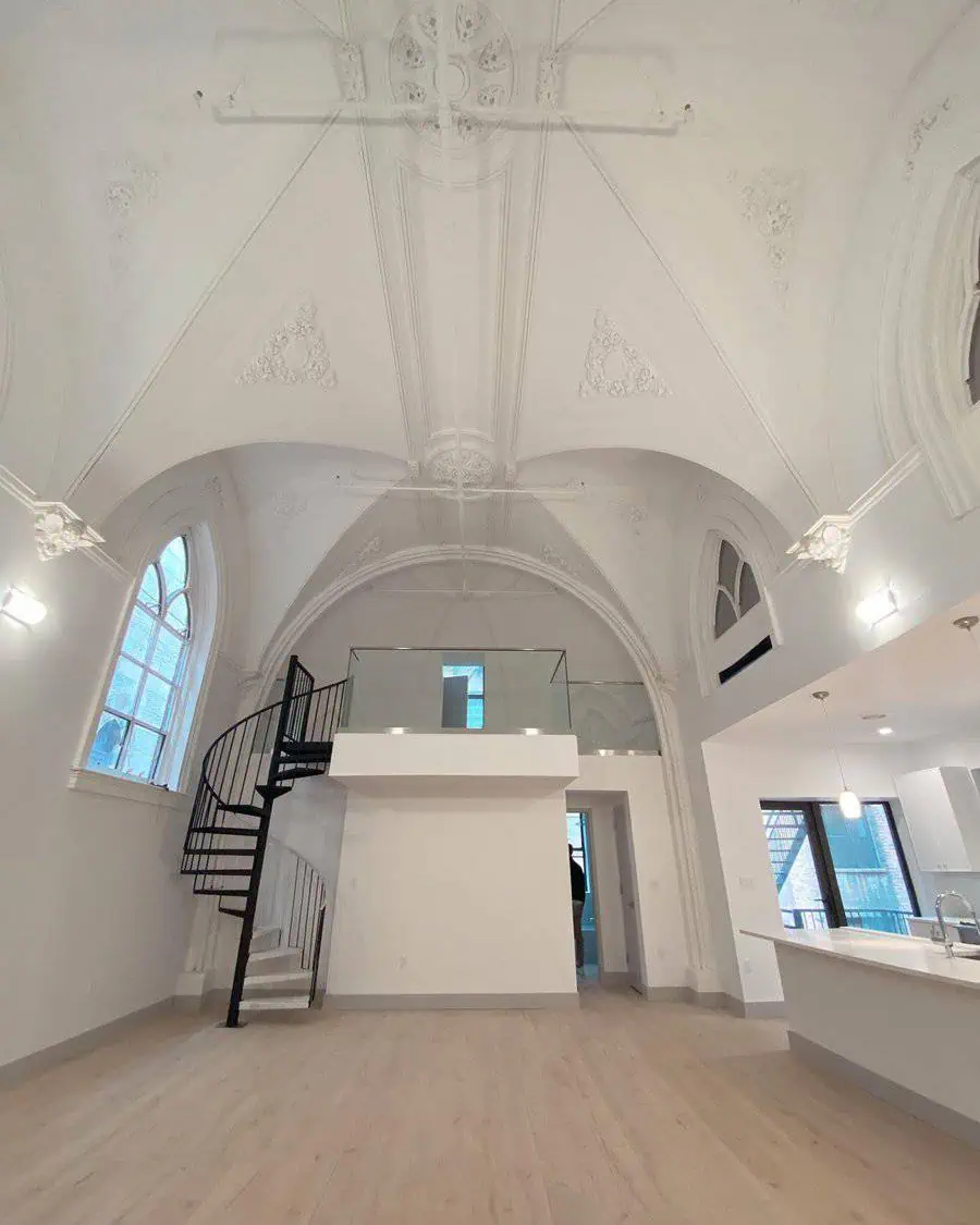 Gothic vaulted ceiling with ornate plasterwork, spiral staircase, and loft in a bright, opulent living area.
