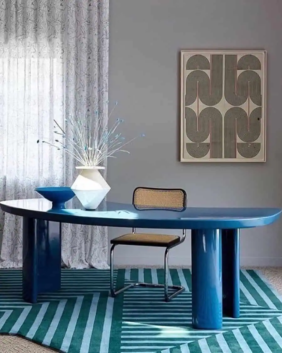 Modern home office featuring a bold blue desk, geometric rug, and minimalist decor for a balanced yet eye-catching setup.