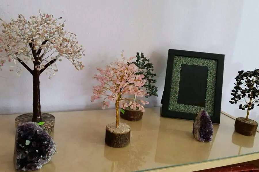 Crystal trees with rose quartz, jade, and amethyst crystals on wooden bases, promoting positive energy and adding charm to the space.