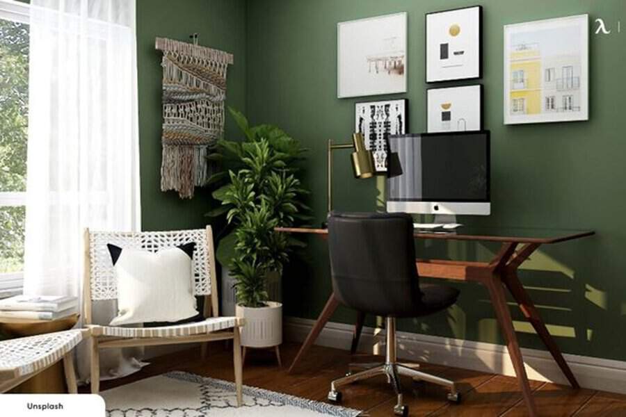 Home office with green walls, a wooden desk, and plants, creating a vibrant yet calm atmosphere for productivity.