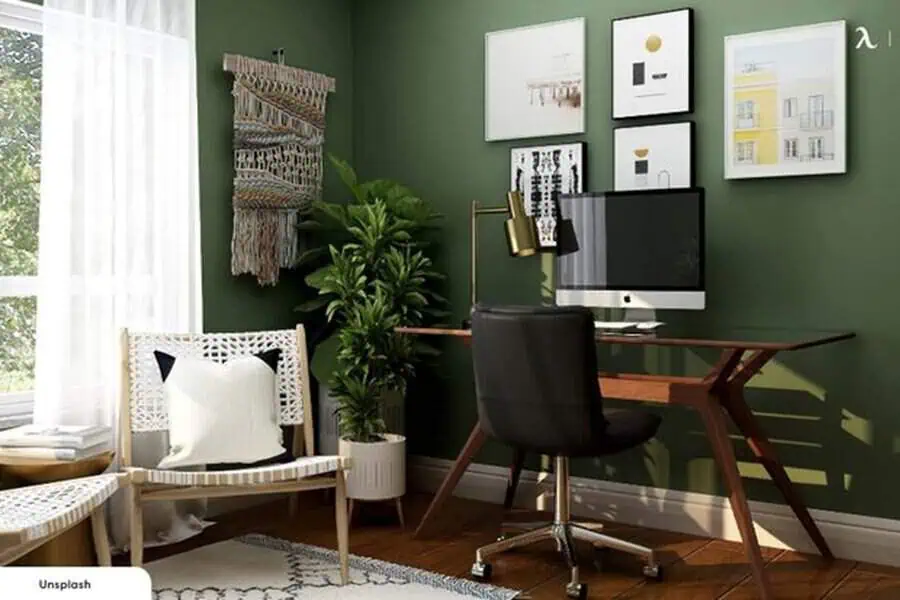 Home office with green walls, a wooden desk, and plants, creating a vibrant yet calm atmosphere for productivity.