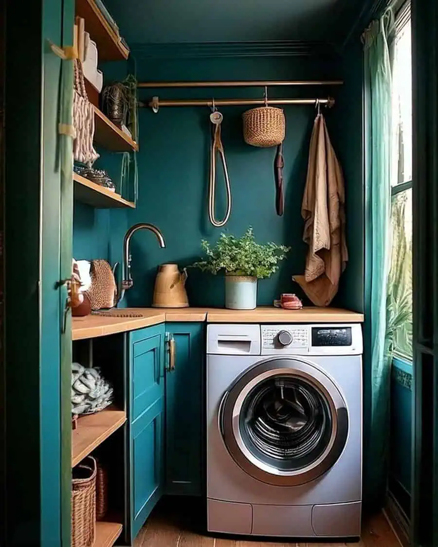 Teal laundry nook with wood counter, brass rod, open shelves, and front-loading washer.