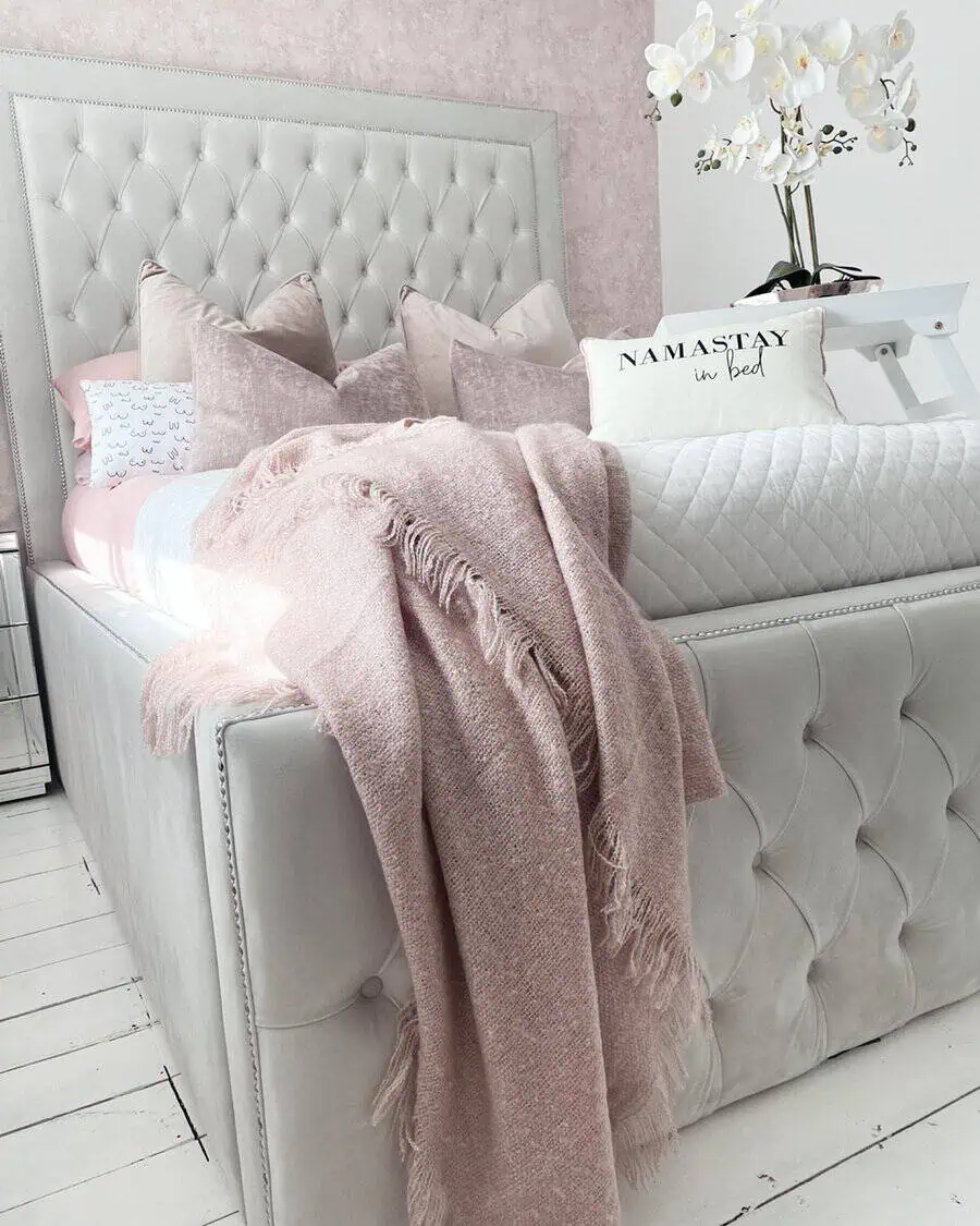 Layered textiles with a soft pink throw, quilted bedding, and plush pillows create a cozy and elegant bedroom retreat.