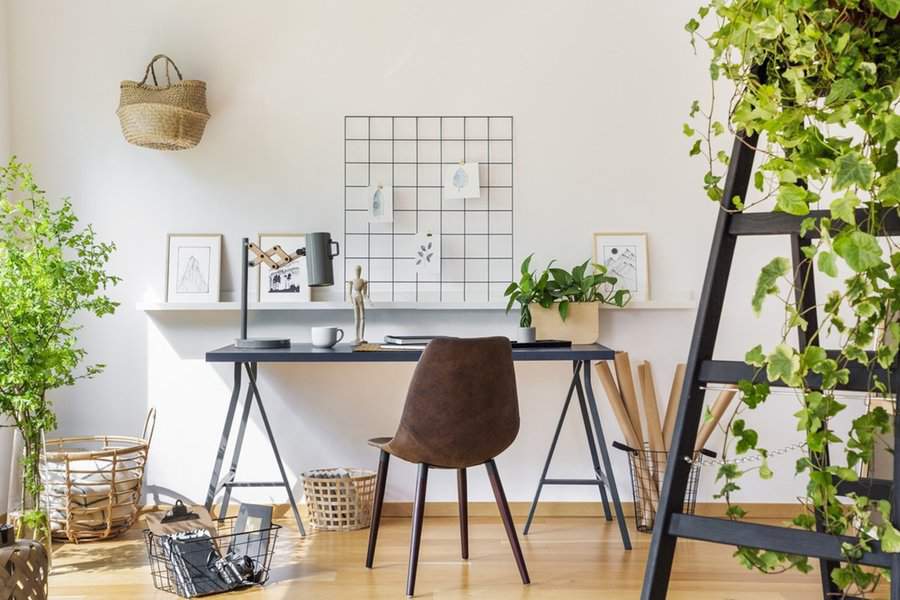 Modern minimalist home office with a functional grid wall, plants, and simple decor for a peaceful, organized environment.