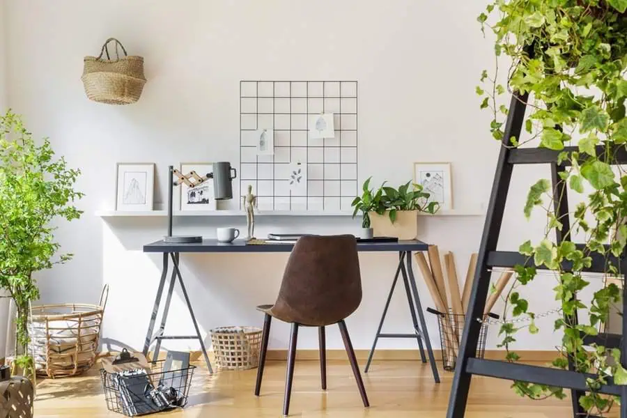 Modern minimalist home office with a functional grid wall, plants, and simple decor for a peaceful, organized environment.