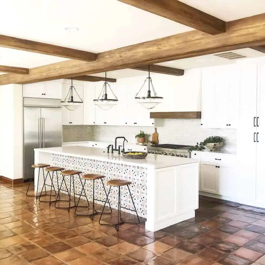 Spanish-style kitchen with open shelving, woven baskets, ceramic decor, and fabric-covered lower storage for a rustic, collected look.