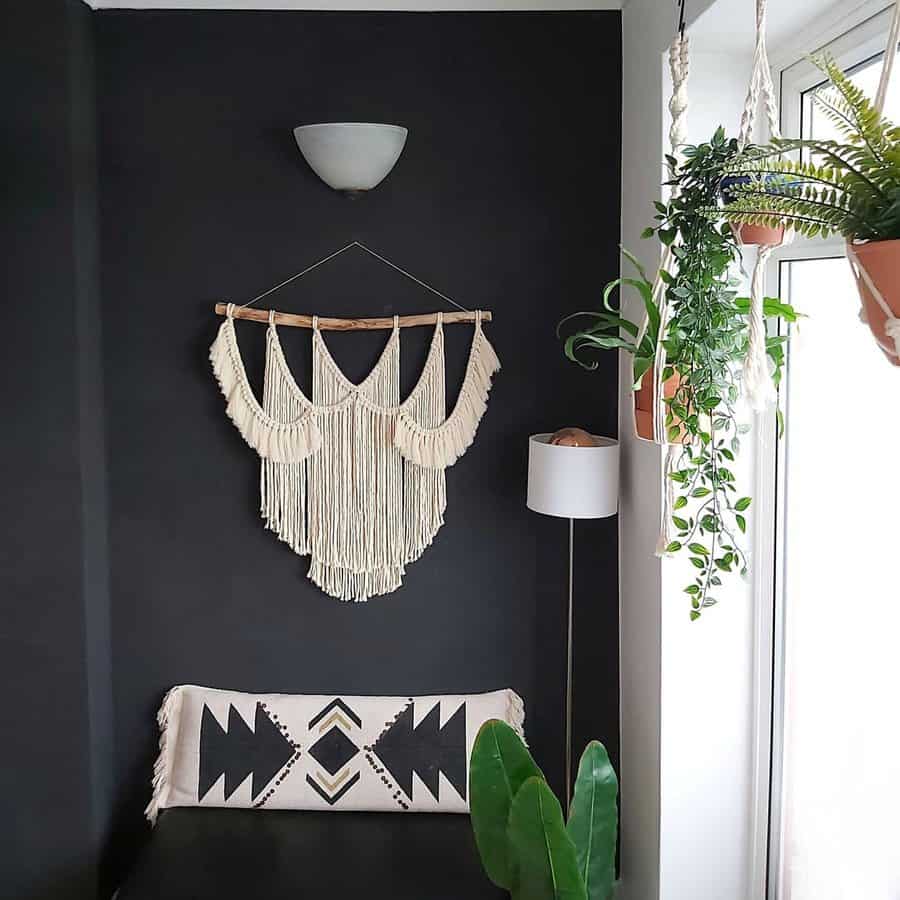 Dark corner with a large boho macrame wall hanging, potted hanging plants, and a neutral tribal pillow for a relaxed, eclectic look.
