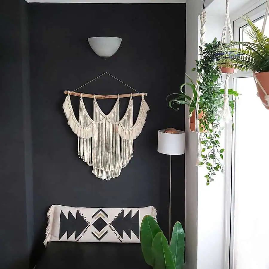 Dark corner with a large boho macrame wall hanging, potted hanging plants, and a neutral tribal pillow for a relaxed, eclectic look.