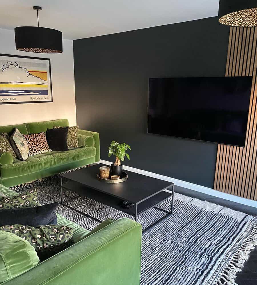 Living room featuring green velvet sofas, a black accent wall, leopard-print pillows, and a sleek black coffee table for a bold look.