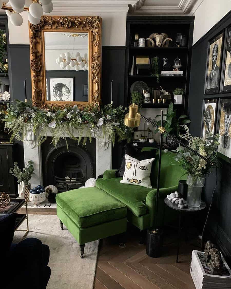 Dark living room with a gold mirror over the fireplace, black walls, and a green velvet chaise adding bold contrast.