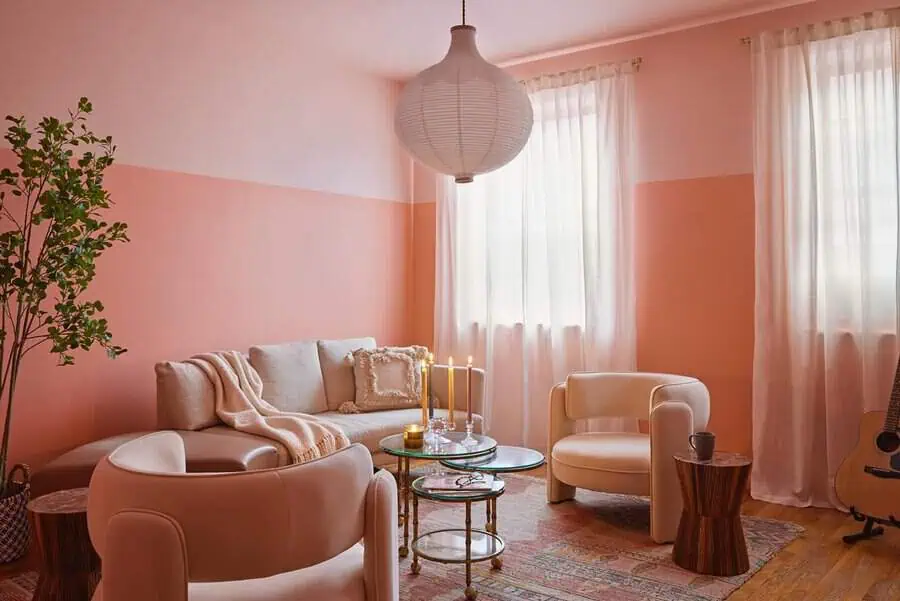 Peach two-tone living room with neutral seating, sheer curtains, and a low glass table creating a soft, welcoming space.