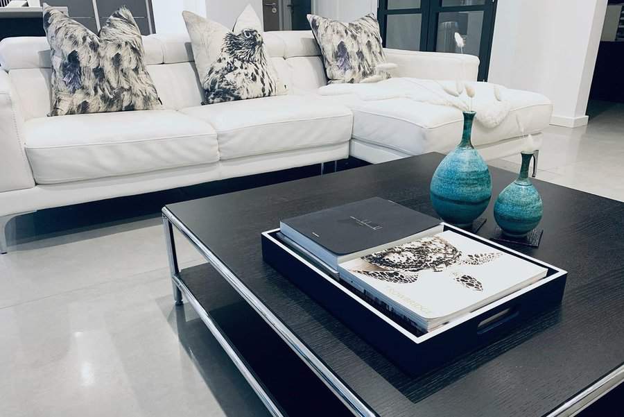 White sofa with monochrome pillows, teal vases on a black coffee table, adding a bold color pop in a sleek, modern living room.