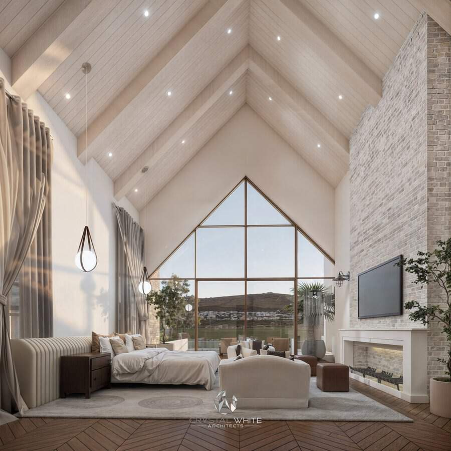 Bedroom with cathedral ceiling, brick fireplace, large window wall, neutral palette, and pendant lighting.