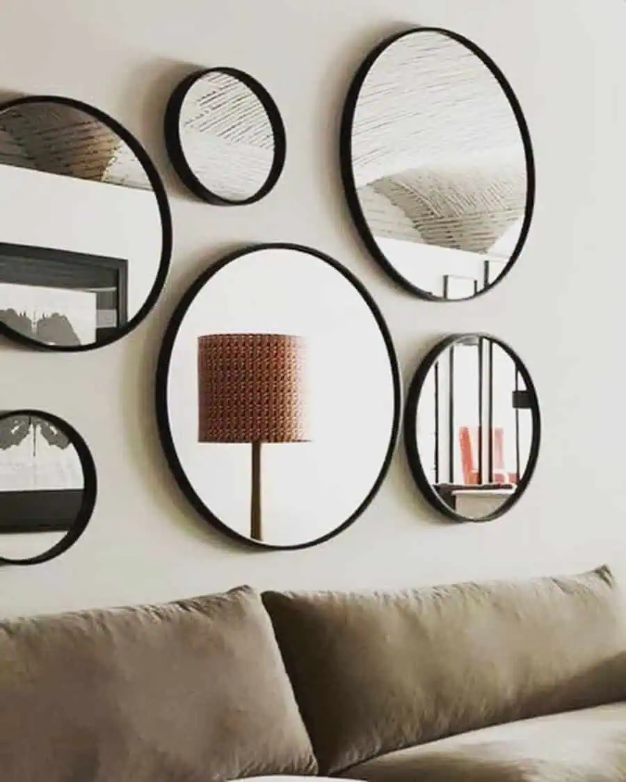 A collection of round mirrors arranged above a sofa, adding style and depth to a minimalist living room.