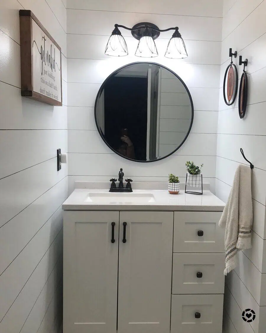 Stylish round mirror and minimalist decor in a bright bathroom with light fixture, sink, and small plants.